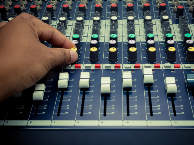 Audio engineer adjusting a mixing board